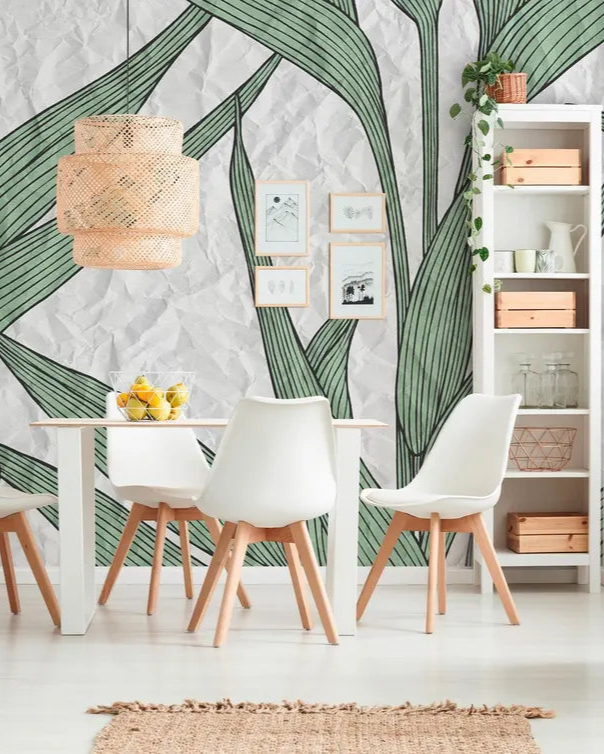 Modern dining room with green leafy wallpaper, white chairs, and wooden tables.